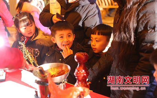 小朋友舔了一口糖画。图片来源：湖南文明网 记者 彭团 摄