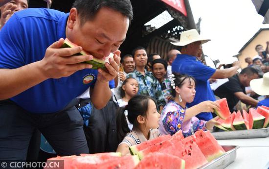 ↑在湖南省湘西土家族苗族自治州花垣县双龙镇岩锣村西瓜节活动现场，人们在进行“吃瓜”比赛。CICPHOTO/龙恩泽 摄