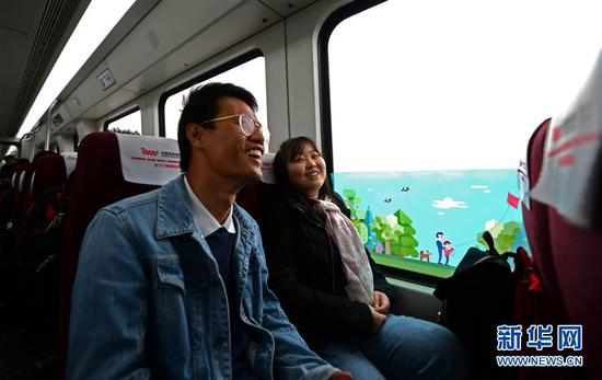1月18日，在中国湖南，刘帅（左）和李静坐在从长沙机场开往长沙南站的列车上。 新华社发（陈振海摄）