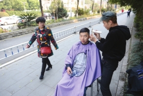 3月12日,长沙韶山南路,宋岚在人行道为顾客理发。图/记者杨旭