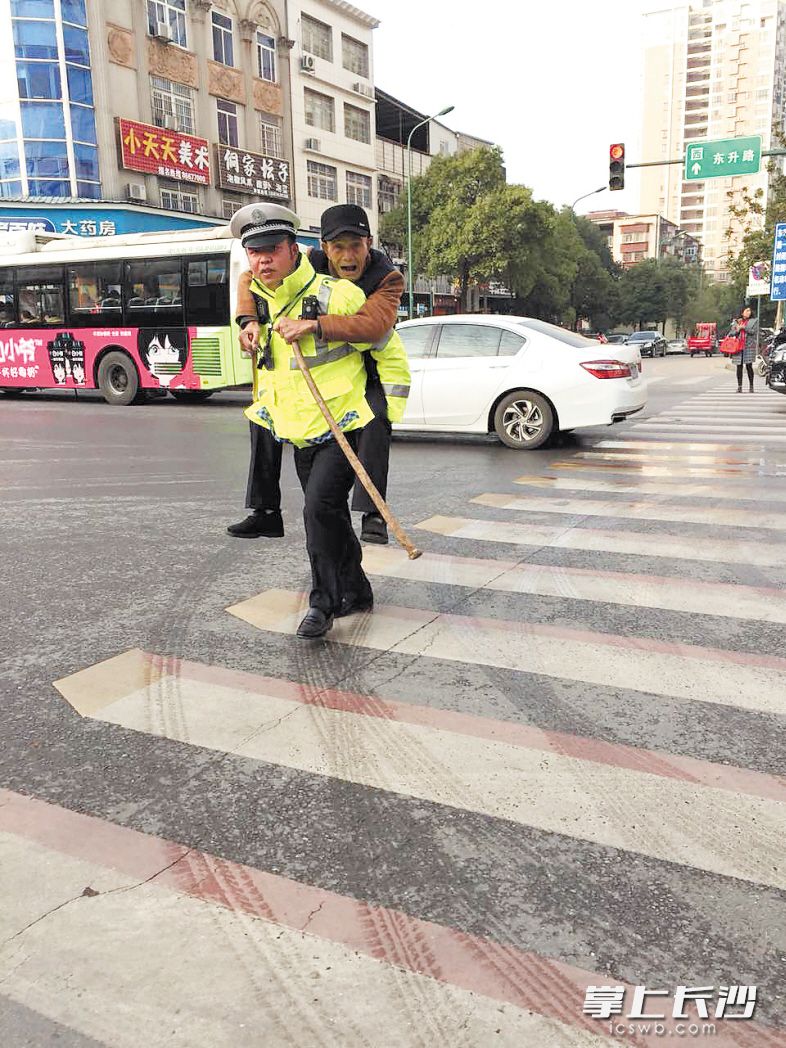 新安中队辅警陈果背老人过马路，被市民拍到发朋友圈，获得许多点赞。长沙晚报通讯员 柳文 摄