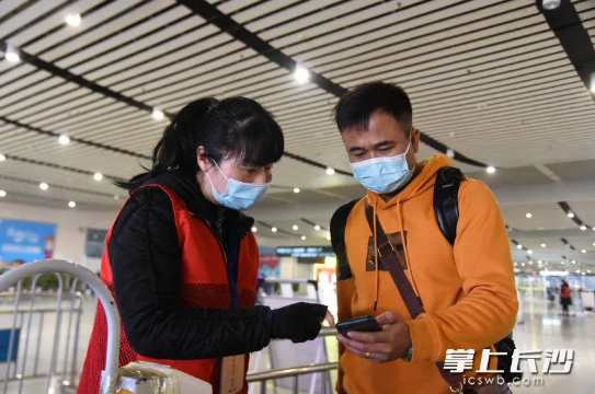 长沙火车南站的志愿者引导乘客出示健康码并进行查验