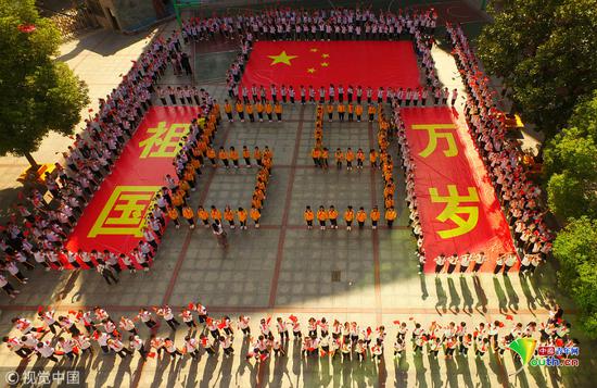 2018年9月30日，湖南省衡阳市雁峰区环城南路小学，学生挥舞着国旗围着“祖国万岁”的祝福标语与国旗合影。