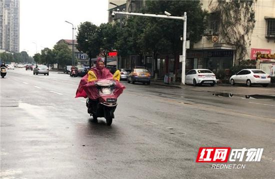 下着细雨的街头,电动车司机穿起了久违的雨衣。