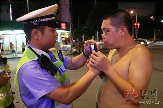 图:执勤民警对驾车男子进行呼气式酒精测试