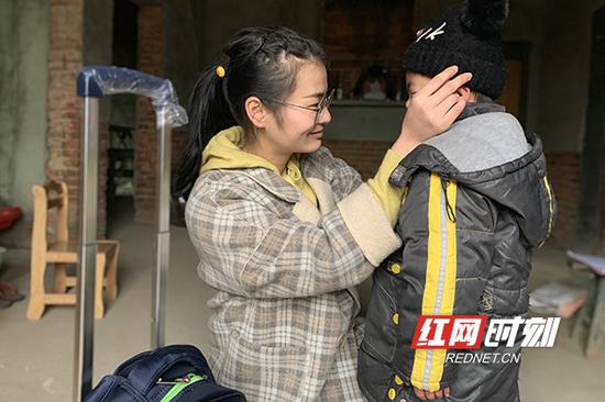 衡阳市雁峰区岳屏镇水东小学教师罗娟为学生周润（化名）买了新帽子并为他细心戴上。