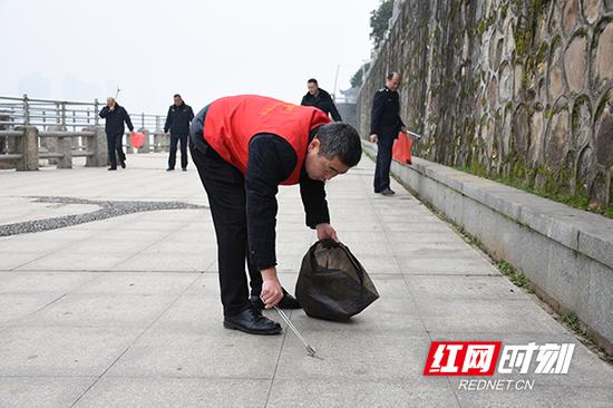 城管干部职工拿着铁夹、垃圾袋等清扫工具投入到卫生大扫除行动中。