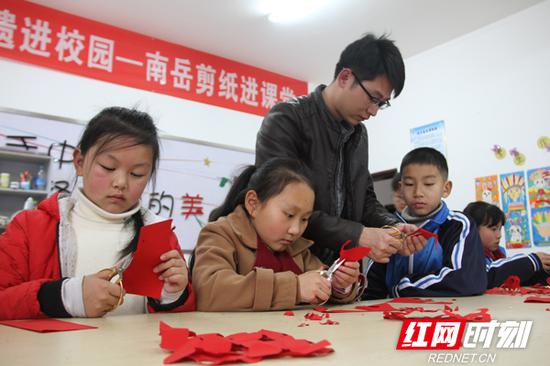 3月13日，在衡阳非遗进校园—南岳区金月完小剪纸课堂上，“南岳剪纸”非遗传承人肖焕手把手教孩子们剪出自己喜爱的花样。