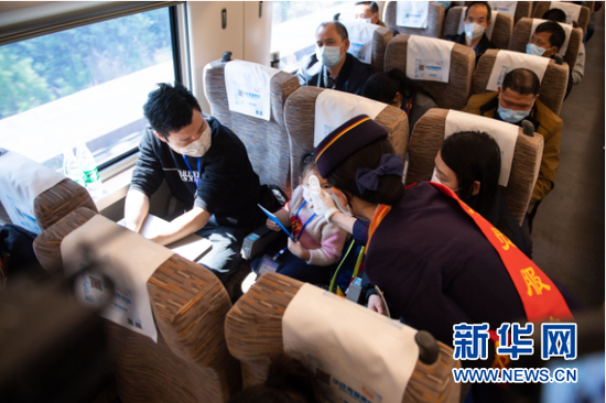 2月24日,在G9628次专列上,列车工作人员为乘客测量体温。