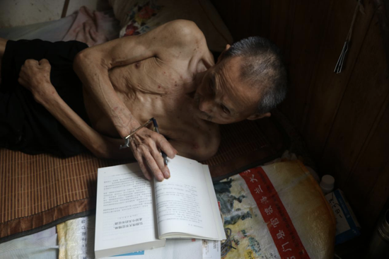 陈集贤老人躺在床上看书