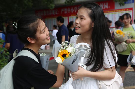 考生们接到家长鲜花后,与考生们在一起交流考试体会,露出了满意的笑容。