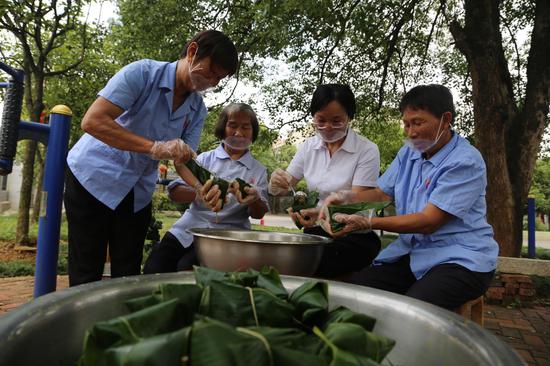 资兴市三都镇敬老院工作人员和老人一起包粽子,他们边包粽子边聊端午节的来历,整过场面淡笑风生。