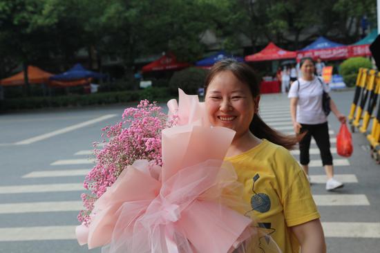 家长手拿鲜花露出笑容,等行孩子走出考场。