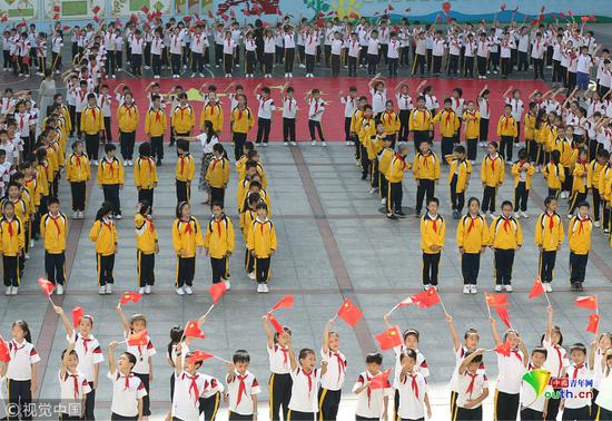 2018年9月30日，湖南省衡阳市雁峰区环城南路小学，学生们挥舞着小国旗与巨幅国旗合影。