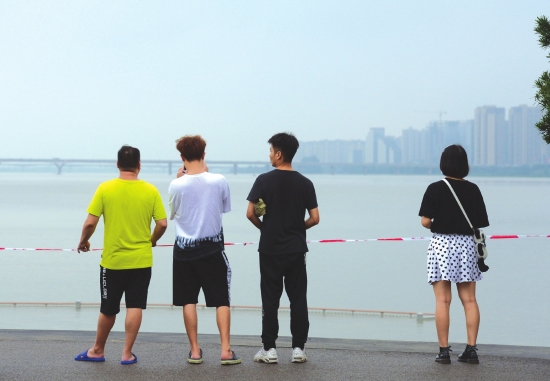 7月10日,长沙橘子洲景区,亲水平台已被完全淹没,游客不得不站在隔离线外。图/记者吴琳红