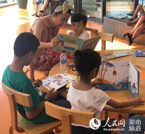 长沙市图书馆内家长带着孩子看书识图。