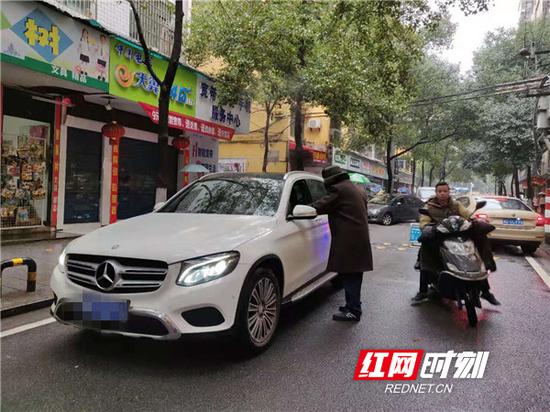 刘魁成老人在引导车辆通行。