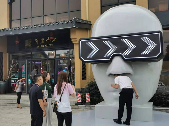 游客打卡巨型“人脸面具像”