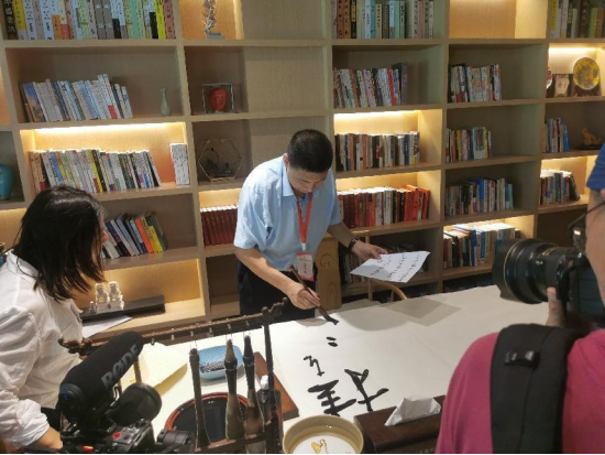 ▲中国作家协会主席团委员、河北省作家协会主席关仁山挥毫写下“挂在瀑布上的千年古镇”