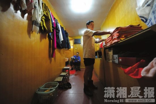 11月27日,长沙新沙池澡堂内,搓澡工谭师傅正在整理供顾客使用的浴巾,另一名搓澡工则为顾客擦着皮鞋。图/记者陈韵骄