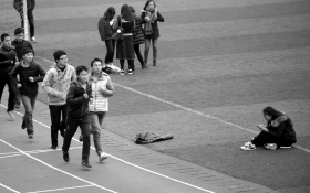 12月7日，湖南某高校，男生在田径场跑步，一些女生在旁边休息。图/记者辜鹏博
