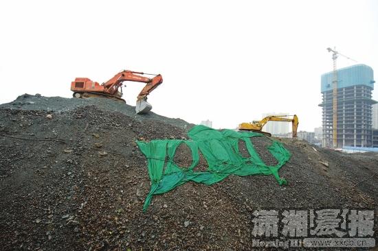 12月24日，开福区福鑫楼附近，施工方对堆放的渣土进行处理。图/记者谢长贵