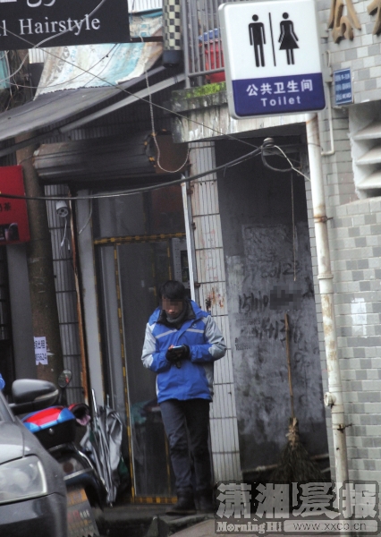 1月12日，麓山南路悦购广场附近，送外卖的工作人员正在撑货披萨实体店门口看手机。该店紧邻公共厕所，中间只隔着一条楼道，店面既没有悬挂招牌，也没有其他标识。图/记者华剑