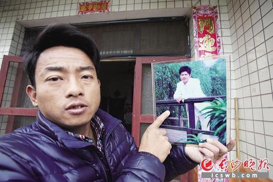 捧着去世弟弟的照片，哥哥周波很伤感。长沙晚报记者 熊伟 摄