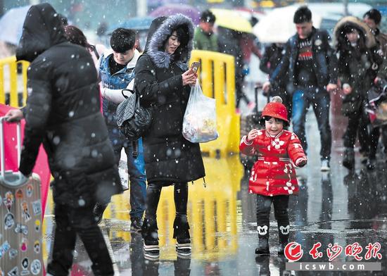 尽管雪伴回家路，但心里却是热的。昨日下午，长沙火车站广场，一位旅客在赶路时不忘掏出手机为孩子拍照留念。　　长沙晚报记者 王志伟 余劭劼 摄影报道