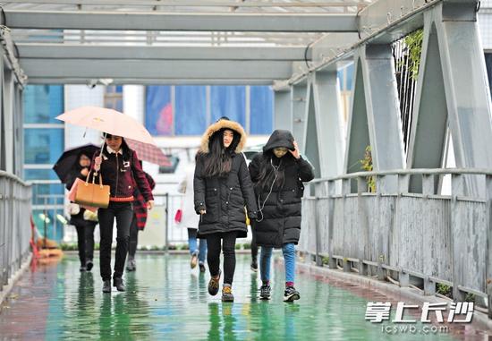 昨日，长沙迎来降温降雨天气，暖和的春天瞬间又回到了冬天。图为营盘路蔡锷路口，市民穿上厚厚的冬装抵御寒冷。长沙晚报记者邹麟摄