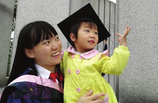 5月27日，湖南师范大学，女硕士毕业生抱着女儿拍毕业照。图/晨报摄友团聂磊