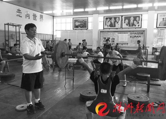 教练李小平指导孩子们练习举重。（资料图片）