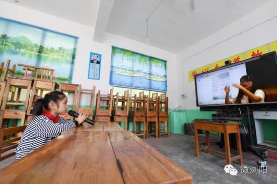 长沙咸嘉湖小学的老师通过网络联教为张秋香上音乐课，她积极地跟着视频另一端的老师哼唱着歌曲。