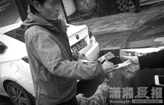 2月8日,长沙人民西路与黄兴广场交会处的路边,一名男子在向车主收取停车费。图/记者陈正