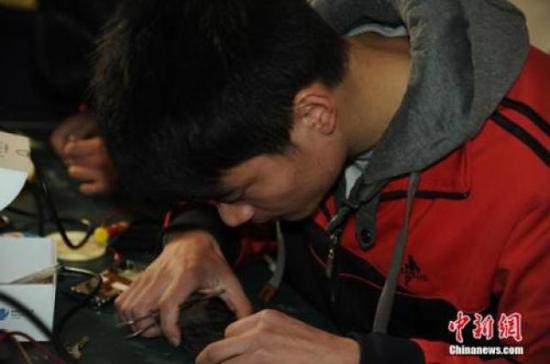 ↑资料图：图为安徽省特殊教育中专学校一名学生正在维修手机。