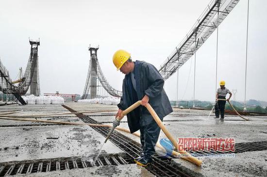 施工人员在冲洗桥面板接缝，以便进行浇灌湿接缝施工。