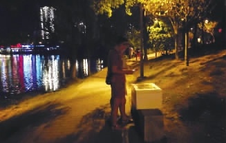 8月28日晚7点，长沙市月湖公园，市民在湖边石凳上的无人售货箱上扫码买货。    丁鹏志 摄