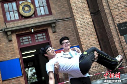 资料图：一名高考考生抱起同学在考场前合影留念。 中新社记者陈骥旻摄