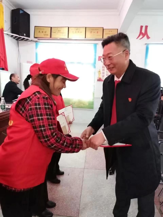 村支书兼村主任罗荣华给受表彰的女村民颁奖