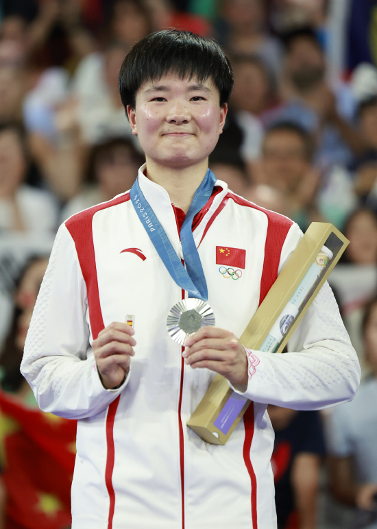 (8月5日,亚军中国选手何冰娇在颁奖仪式上,带着西班牙国旗徽章登上领奖台。 图片来源:新华社)