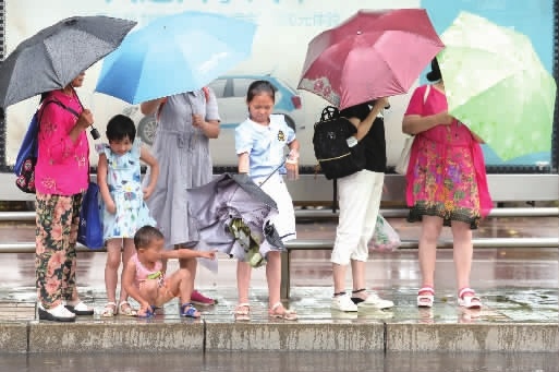 7月22日，长沙市开福区湘江中路开福寺段，市民在公交站避雨、候车。受台风外围云系影响，22日至24日湖南多阵性降雨。 傅聪 唐俊 摄