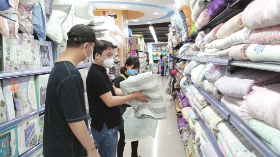 5月20日，长沙理工大学附近的小超市，辅导员程静征（左二）为李文星选购被子。视频截图