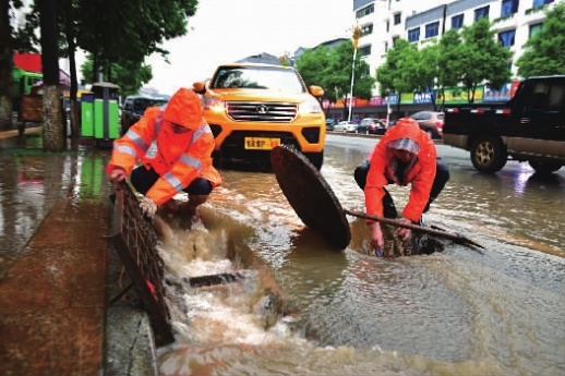 5月30日，怀化市迎丰东路石门段，市政人员冒雨打开窨井口，排除路面积水。当天，受强降雨影响，该市城区部分路段出现积水，市政人员逐一打开积水路段的窨井口，排除积水，并在每一个窨井旁安排专人看守，守护过往行人安全。 陈湘清 摄