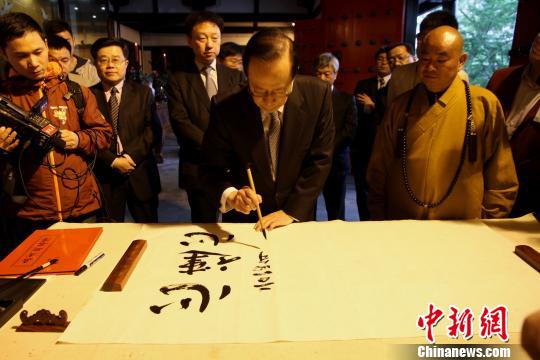 图为2014年4月21日,日本前首相福田康夫参观扬州大明寺鉴真纪念堂。福田康夫在鉴真纪念堂内提笔蘸墨、手书汉字“心连心”,并用中文落款“福田康夫”赠予大明寺。(资料图) 崔佳明 摄