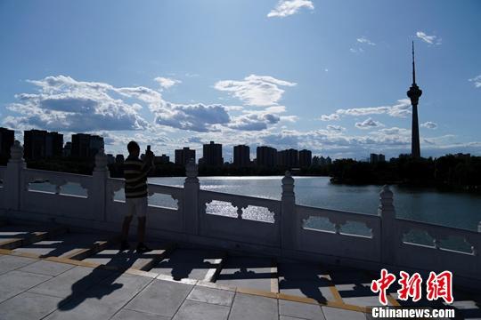 资料图：2019年8月29日，北京玉渊潭公园，一游客拍摄蓝天白云美景。中新社记者 张兴龙 摄