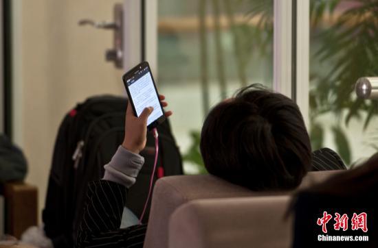 资料图:男子用手机阅读小说。 中新网记者 翟璐 摄