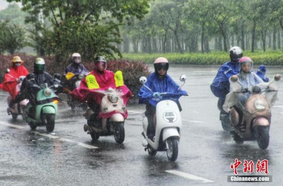 资料图:民众在雨中出行。 翟李强 摄