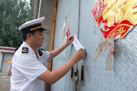6月6日,河北廊坊广阳区卫健局工作人员给涉事企业的大门贴封条。新京报记者 王飞 实习生 陈婉婷 摄