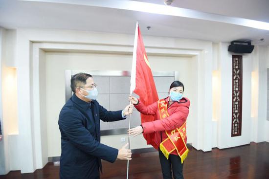 曹主凤（右）代表宿迁援湖北医疗队接过党旗