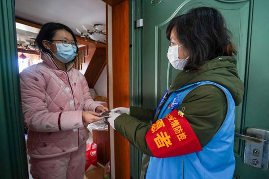 2月17日,南京市建邺区南苑街道兴达社区网格员范璐(右)为辖区内一位居家观察的居民送去体温计和酒精棉签。新华社记者李博摄